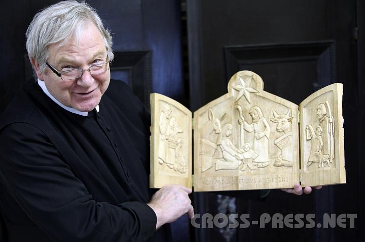 2009.12.03_11.17.20.jpg - P. Martin zeigt eine Besonderheit: seine "kleine Jahreskrippe", 2007 entstanden, deren Teile er jeweils beidseitig geschnitzt hat mit Szenen von der Verkündigung bis zur Himmelfahrt, wobei Geburt und Kreuzigung groß dargestellt sind.